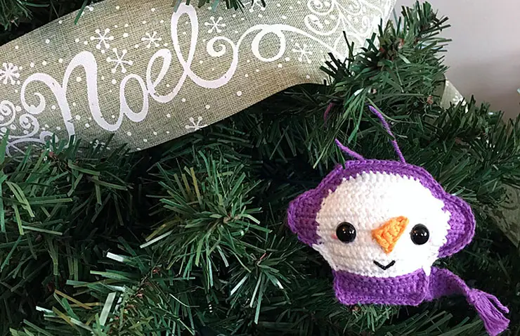 crocheted snowman ornament with purple earmuffs